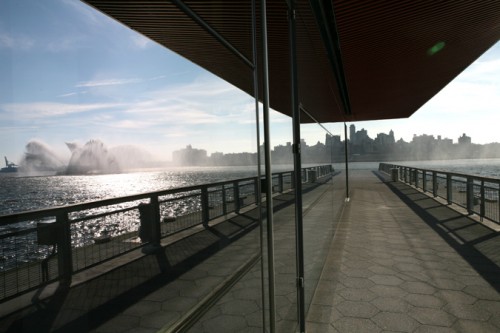 The lower level pavillion reflects a fire boat spouting riverwater. 
