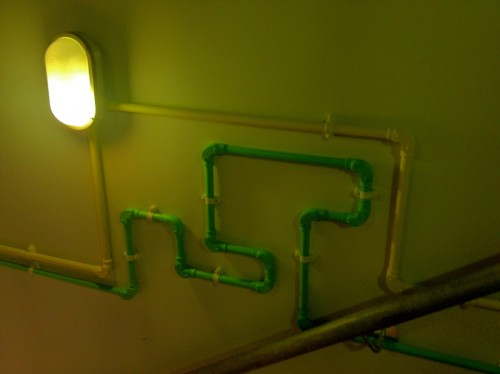 Colorful PVC tubes for lighting meander down a stairwell. 