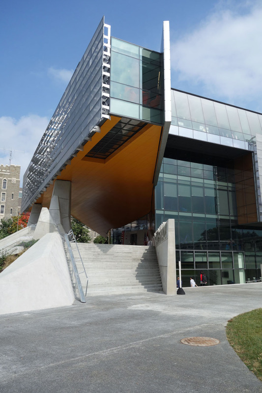 The upper floors extend in a dramatic cantilever to form a sheltered entrance plaza. (Courtesy Cornell University)