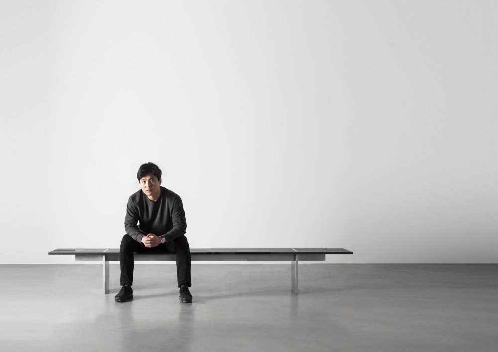 Wonmin Park sitting on a bench from his Plain Cuts collection at the Carpenter's Workshop Gallery