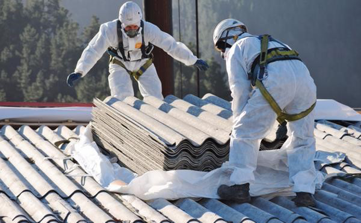 A photo of men working with asbestos tiles on a roof