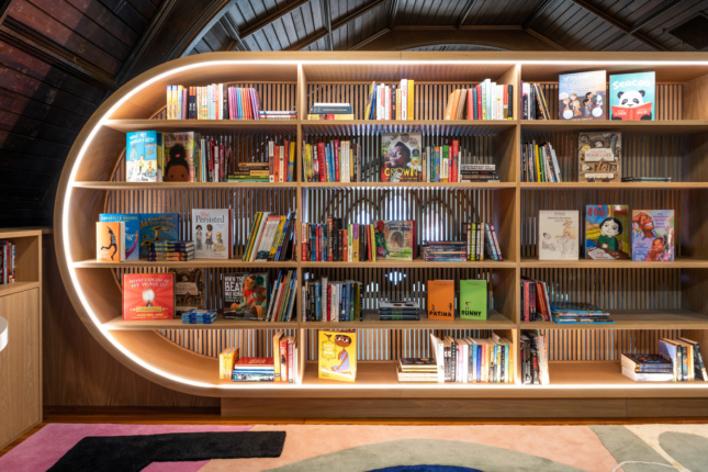The wooden dowels at the back of the bookshelf form a screen that allows light through.