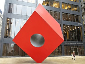A large red cube with a hole in it in front of 140 broadway