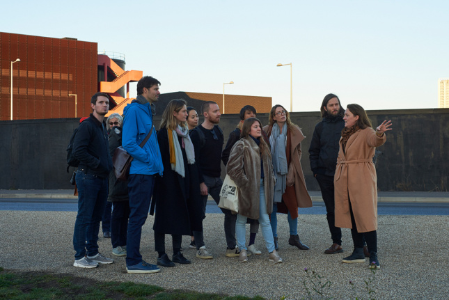 Photo of a group of people standing outside and looking at something off-camera