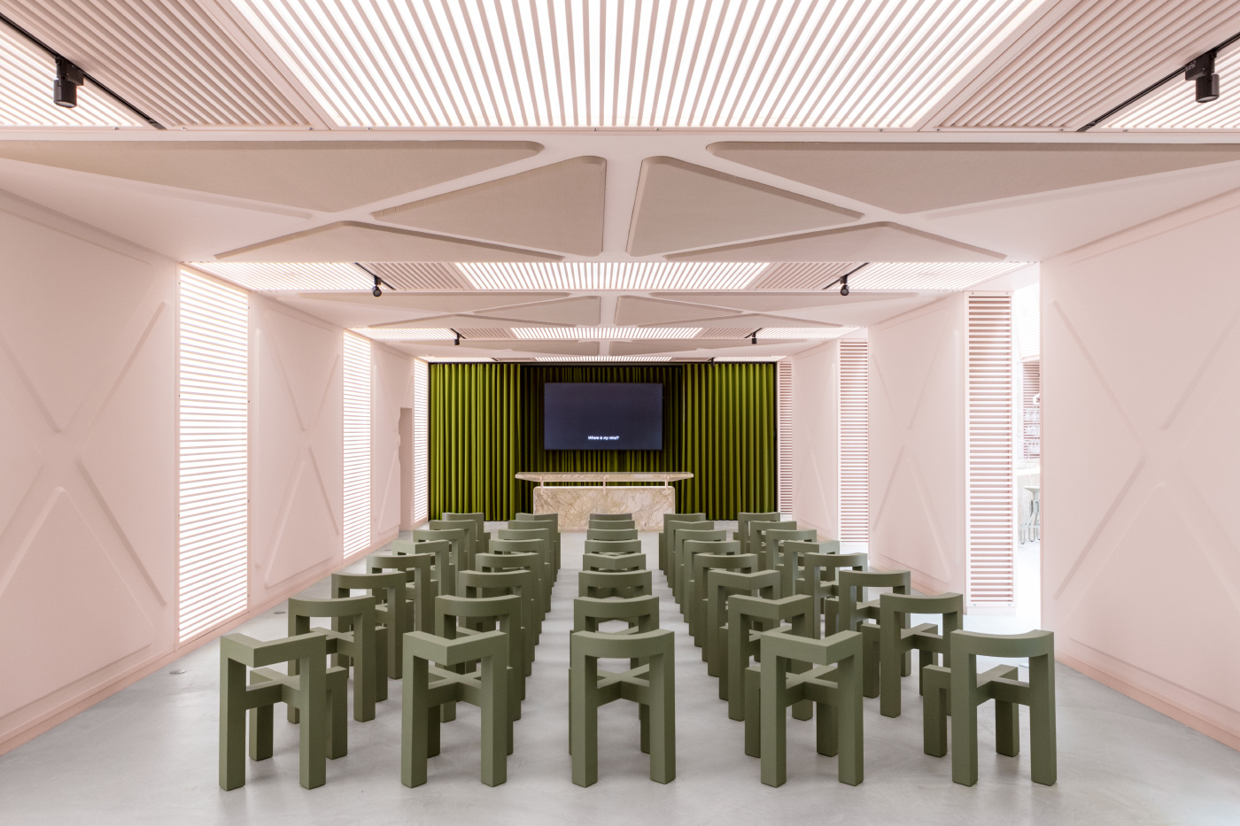 A pink conference room with green chairs