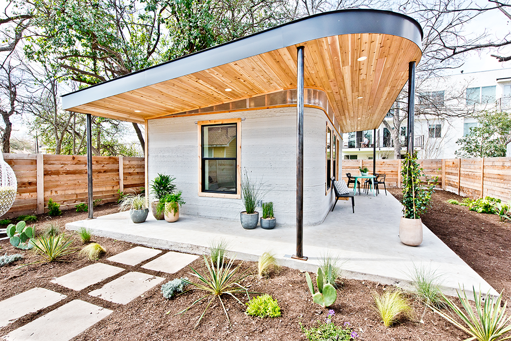 Photo of a small 3D-printed home with a large overhanging wooden roof