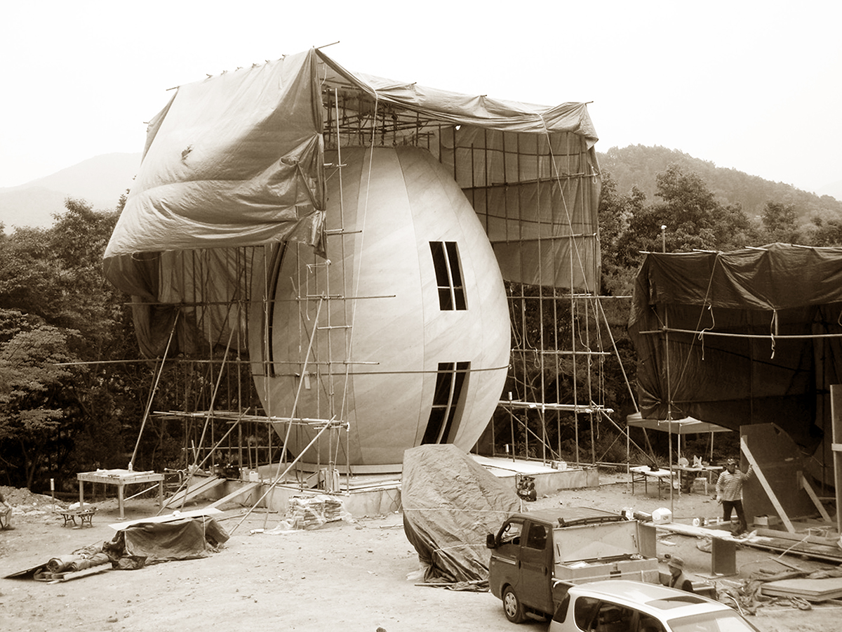 Sepia photo of an egg-shaped building under construction