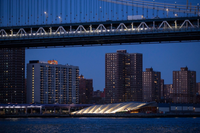 A view of the Manhattan Bridge at night with a lit-up park below
