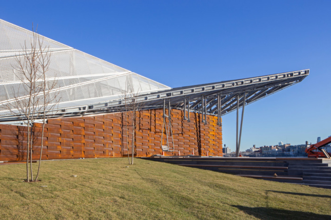 Photo of a long metal wall supported by rust-colored panels on the waterfront