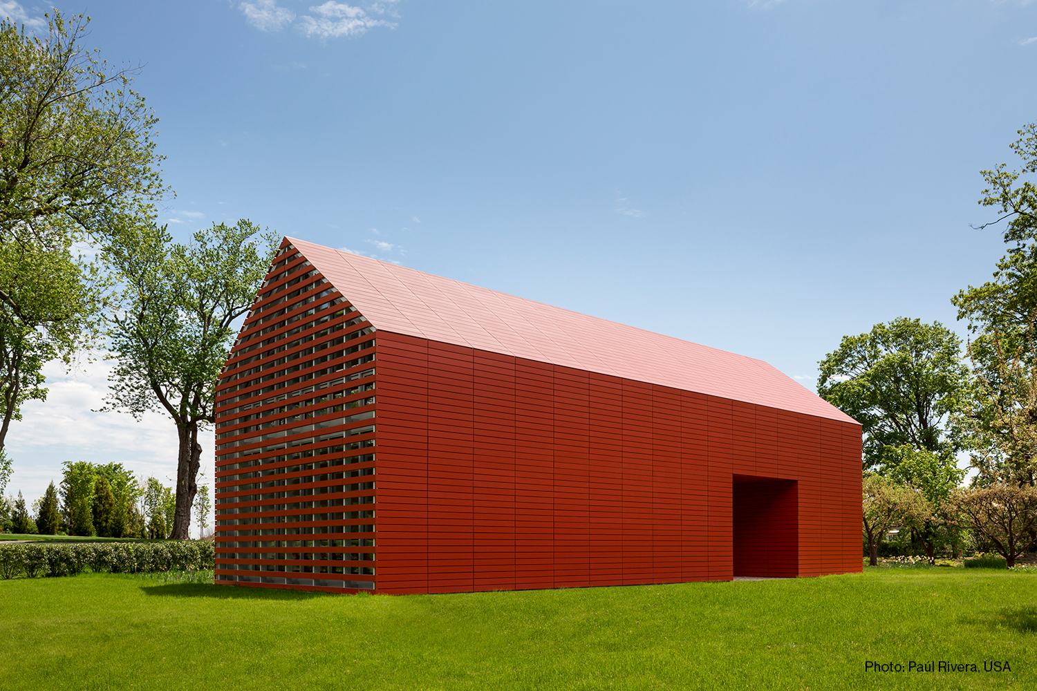 Photo of a red minimalist building in the shape of a barn