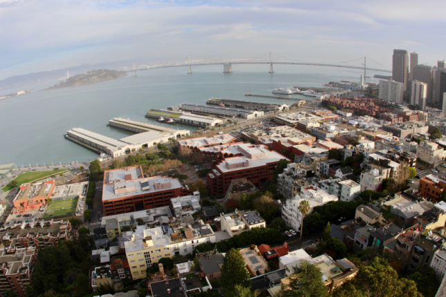 An aerial photo of a bay and waterfront neighborhood spanned by a bridge