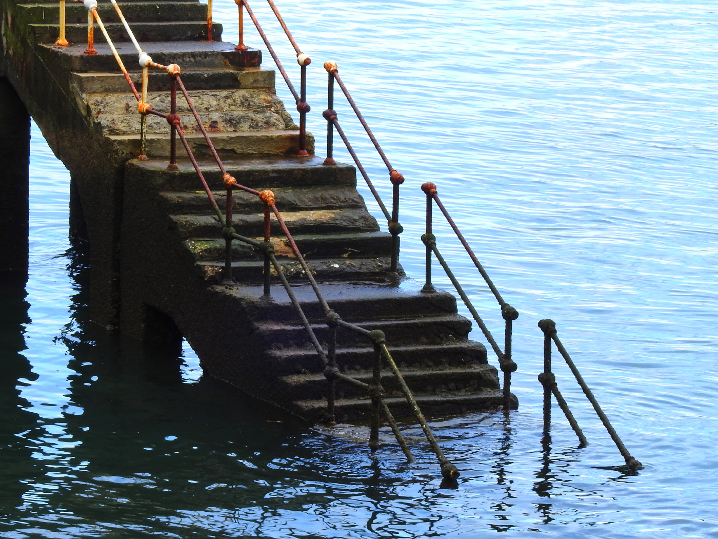 Photo of a set of worn and weathered stairs descending into water