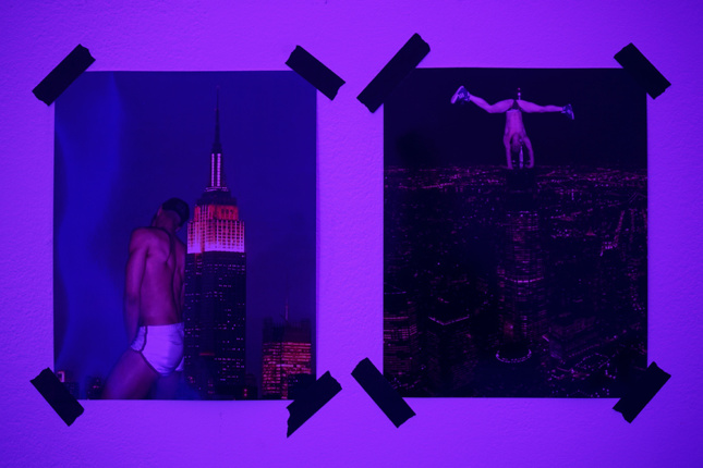 Two postcards taped up with male go-go dancers performing on the Empire State Building.