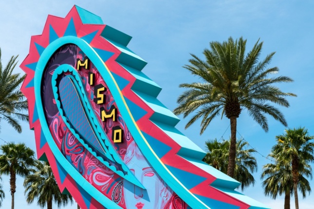 Photo of a brightly colored sign in the desert in the shape of a paisley swirl
