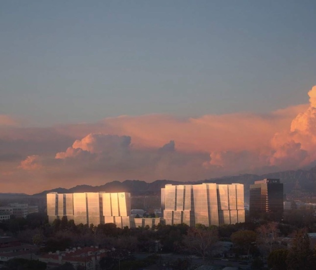 Rendering showing two linked towers with glass skins reflecting the setting sun