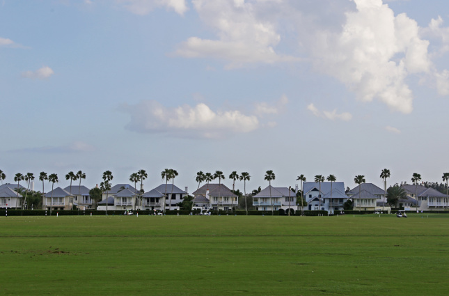 Photo of a row of large houses with a golf course in front of them