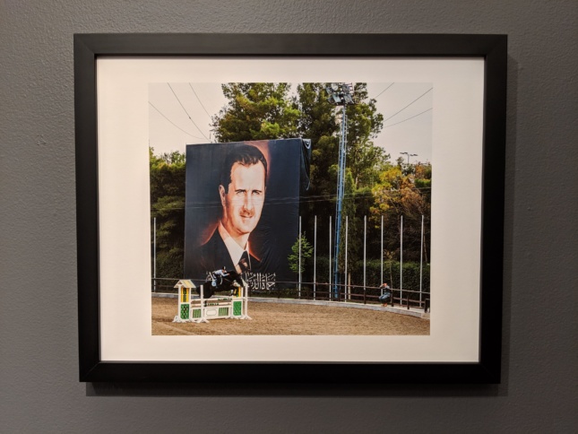 Photo of a photo of an outdoor space with a large mural of Bashar al-Assad