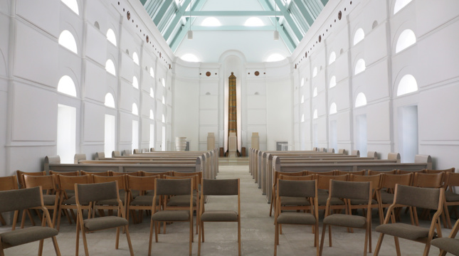 Photo of folding chairs arranged in the interior of a white light-filled chapel
