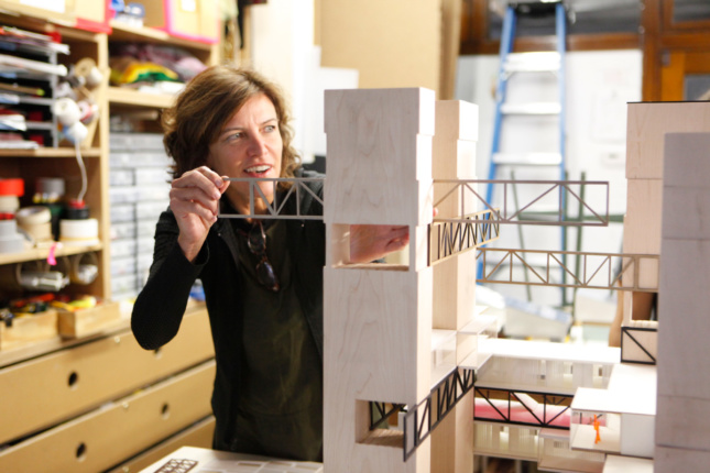 Photo of a woman sliding a piece into an architectural model