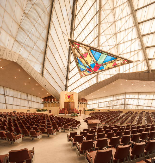 An interior photo of a temple, with a large stained glass triangle and glass walls extending upwards