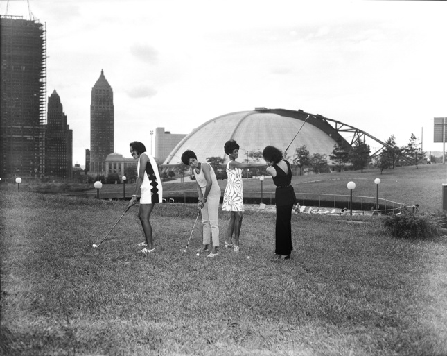 Black and white photo of four people playing golf in downtown Pittsburgh