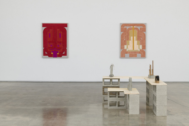 Installation photo of two paintings along with a series of small sculptures mounted on "plinths" made of cinderblocks.
