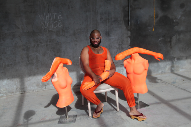 Photo of a person wearing orange clothes sitting in between two orange torsos