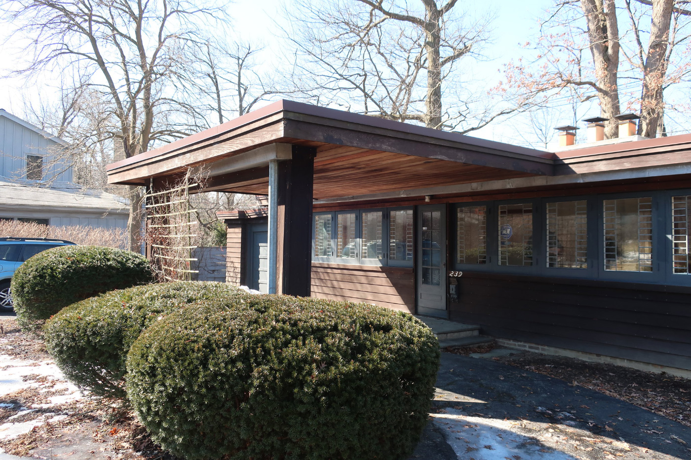 Photo of Booth Cottage, a Frank Lloyd Wright-designed low-slung wooden cottage with leaded windows and an entrance awning