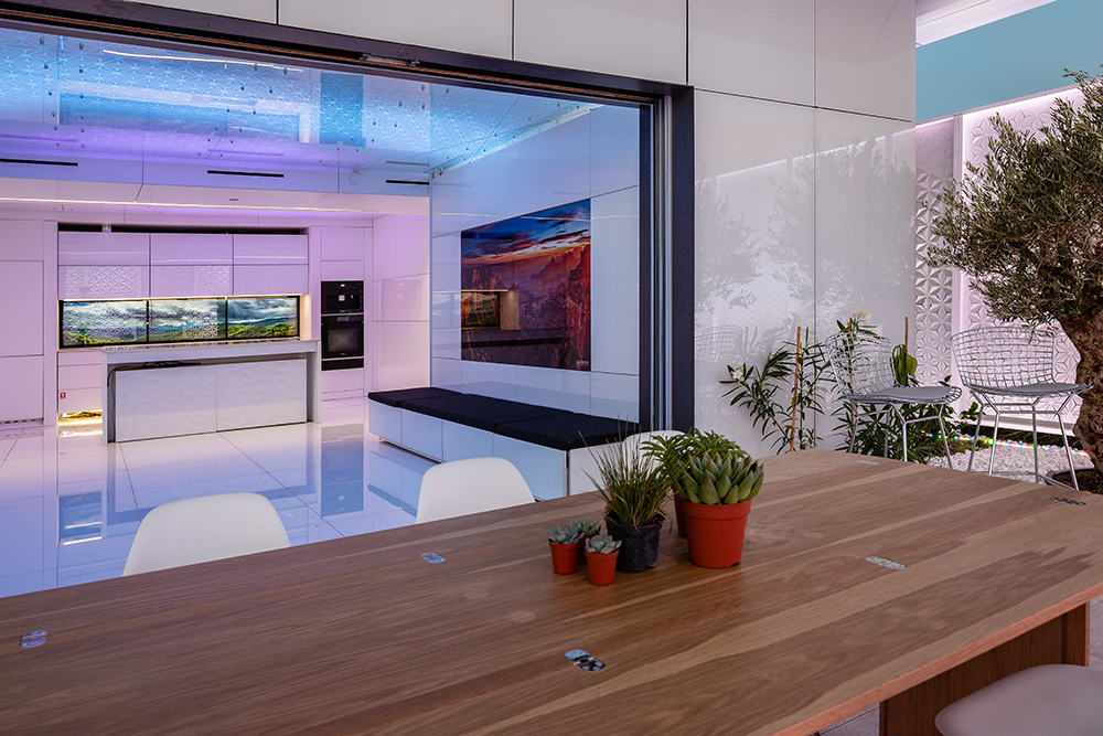 Rendering of a table with succulents in the foreground of a sleek white interior with purple and blue lighting