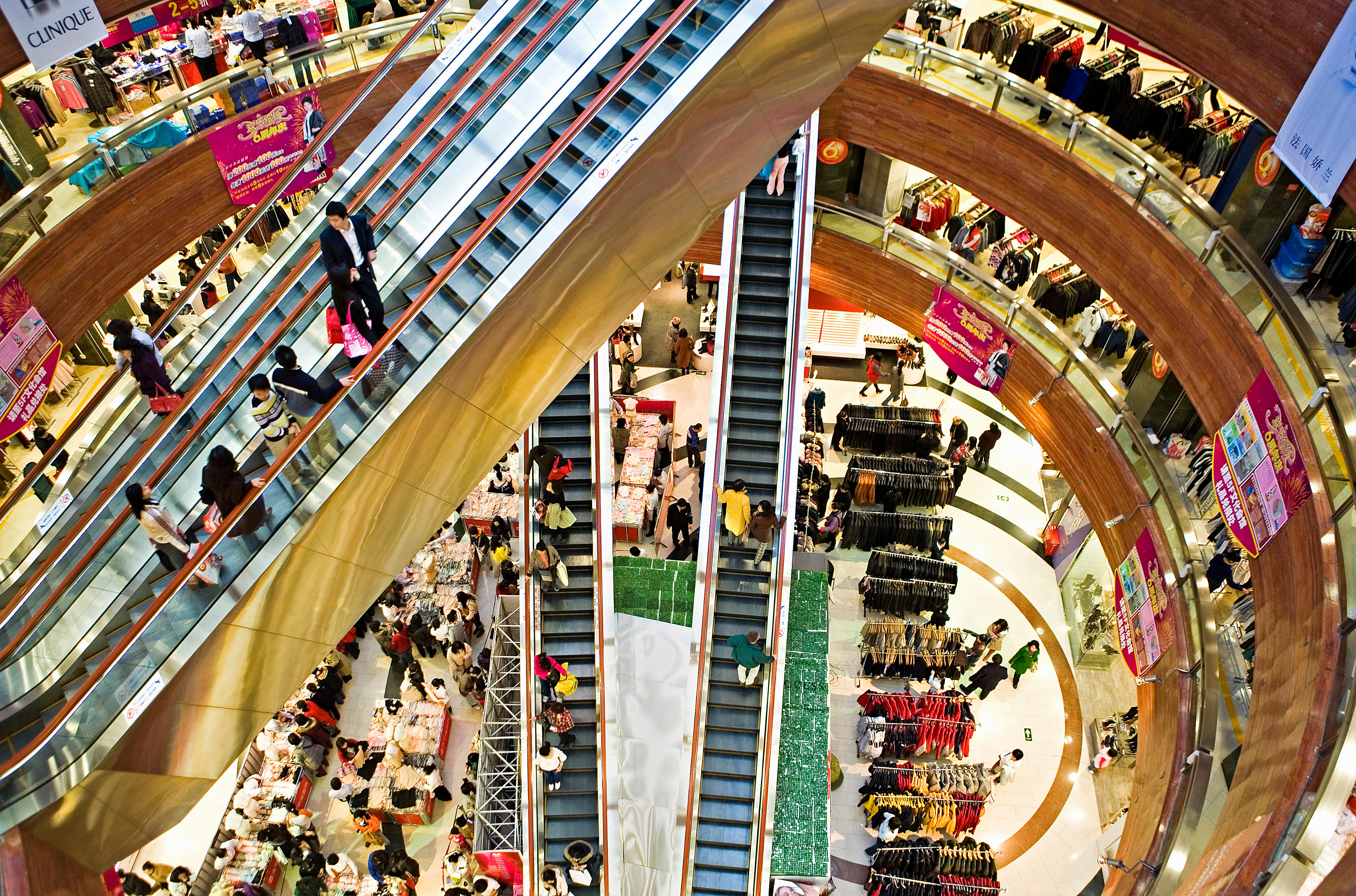 A top-down photo of intersecting gold-colored escalators in a shopping mall