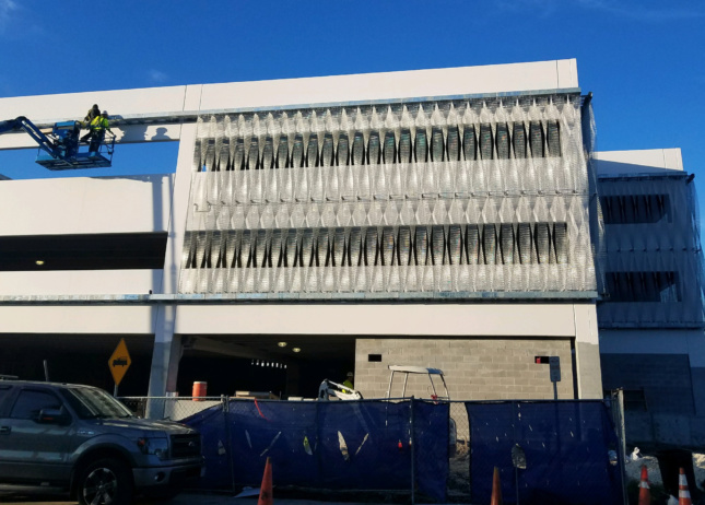 Exterior construction photo showing stainless steel mesh getting put on a facade