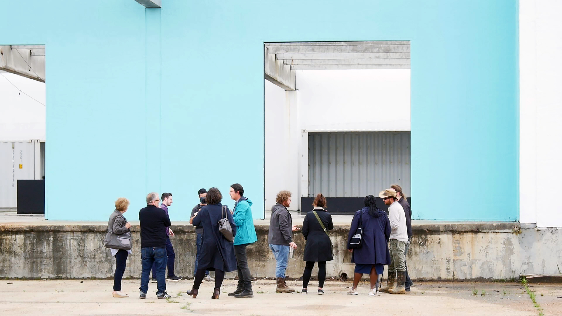 Photo of people standing in front of a light blue building wall