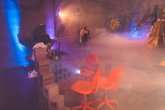 Photo of orange chairs in an empty concrete room with fog in it