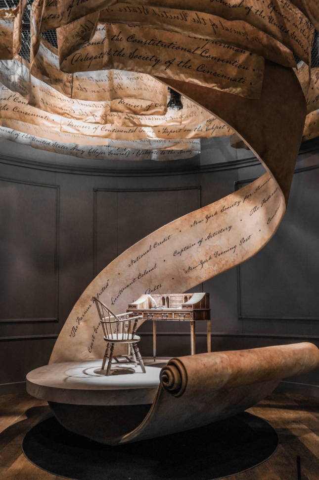 An antique writing desk with a large swirl of parchment that twirls overhead