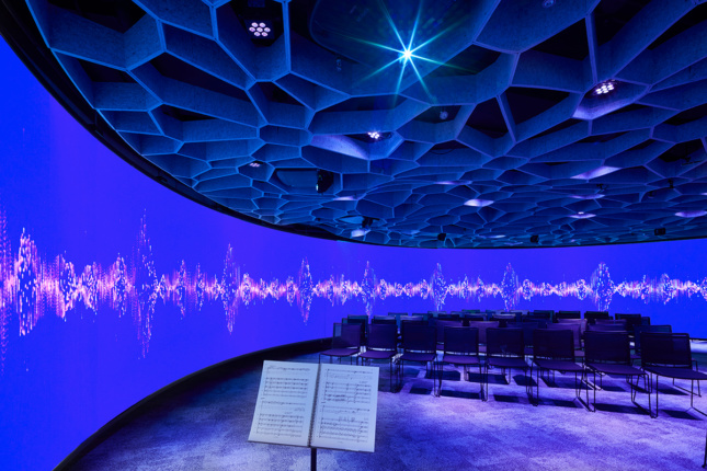Photo of the Octave 9 interior, a round room with digital projections on the walls, mesh on the ceiling, and seats in the middle