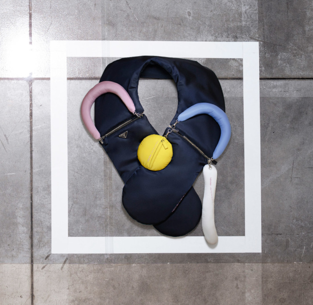 Photo of a black, U-shaped nylon bag with blue and pink handles