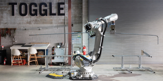 Photo of a robot arm in front of a sign reading "TOGGLE"
