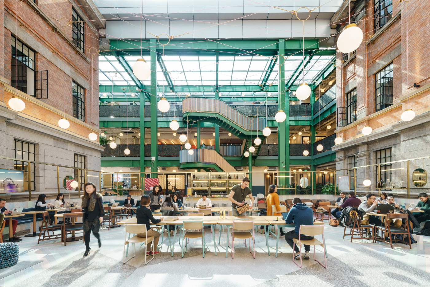 Photo of a common atrium bounded by brick buildings and covered with a green skylight