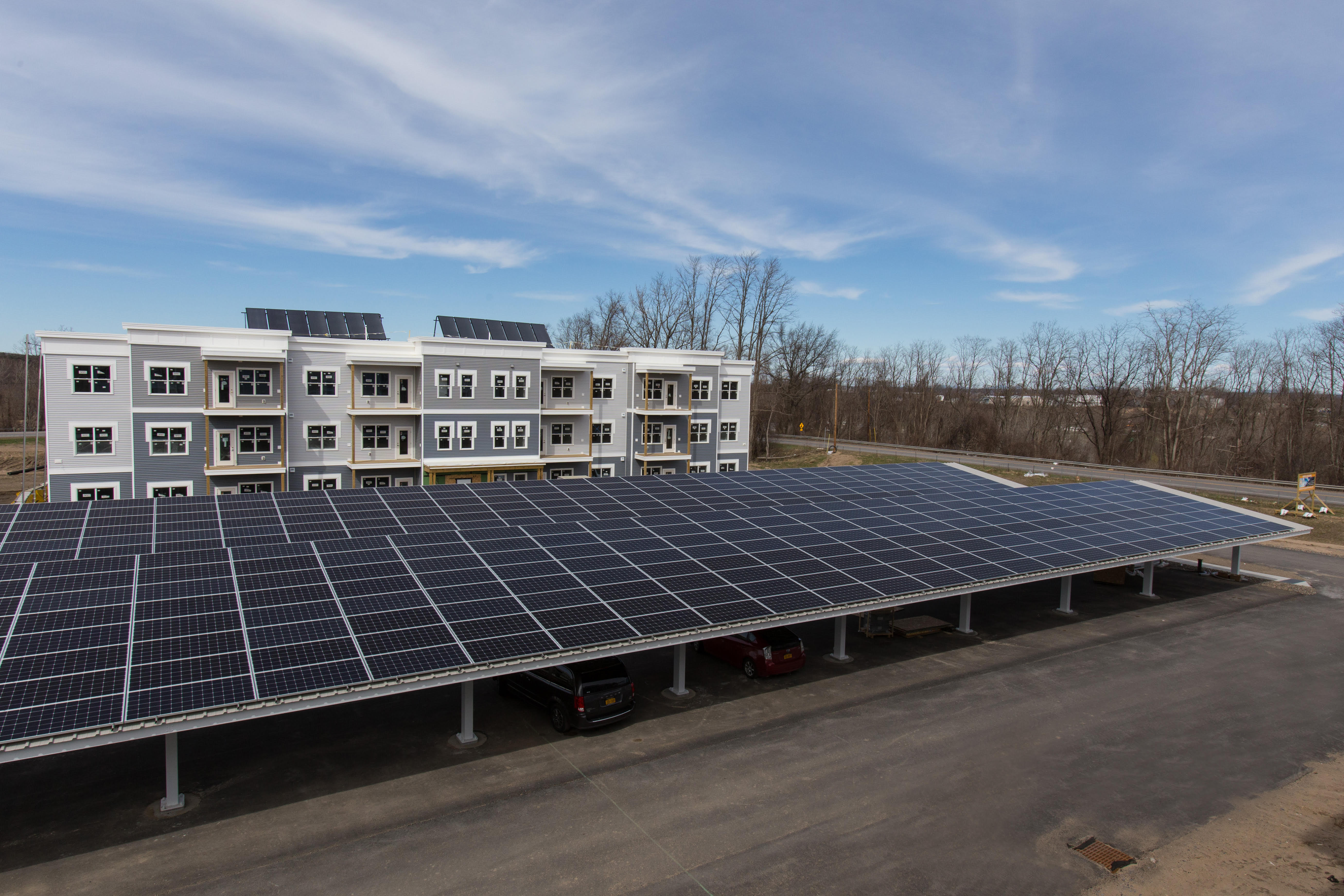 Photo of parking lot covered with solar panels with an apartment complex in the background