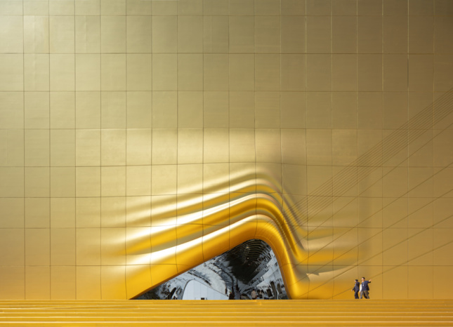 Golden skin on a building that lifts in the center to reveal a mirrored section