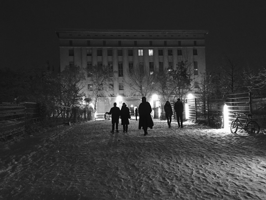 Black and white photo of people walking through the snow to Berghain in an old East Berlin power plant