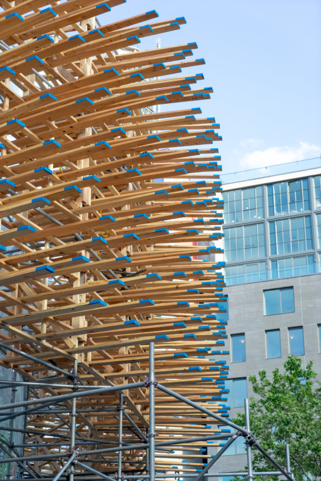 Hundreds of two-by-six planks suspended in the air with blue caps at the end