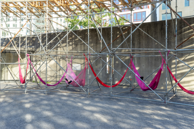 Red and pink hammocks hung between metal scaffolding