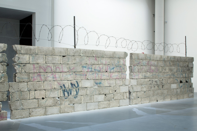 A 39-foot-long concrete block wall topped with razor wire