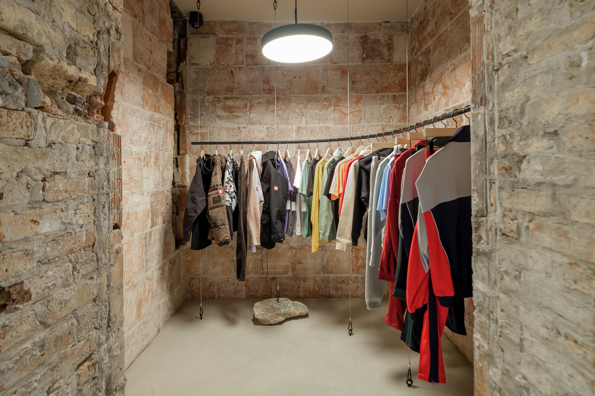 Photo of clothes hanging in room with unfinished stone and brick walls
