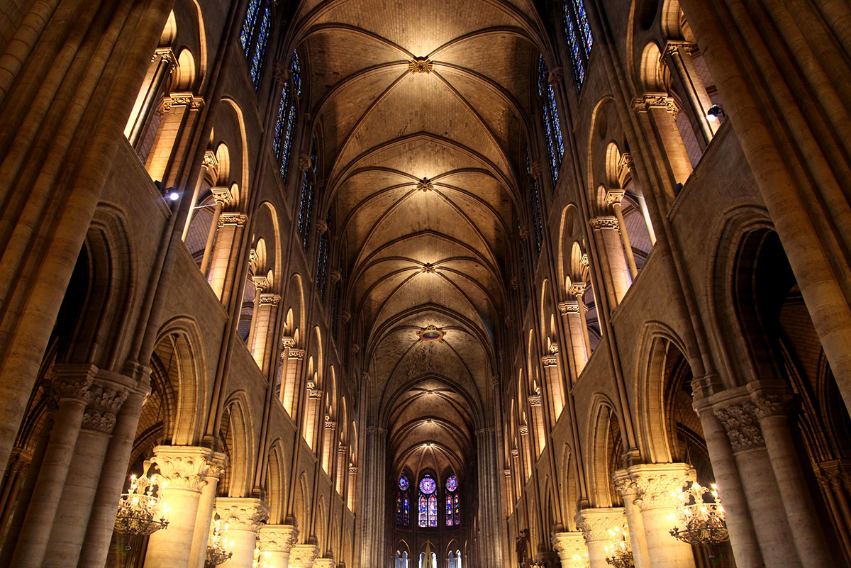Image of inside Notre Dame cathedral with candle lit vaults and columns