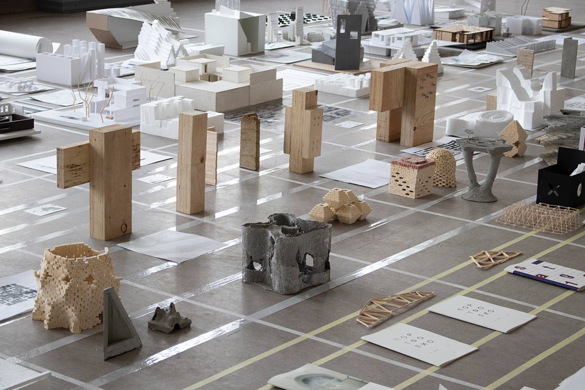 Close up image of artifacts made from wood and concrete displayed on floor in a grid