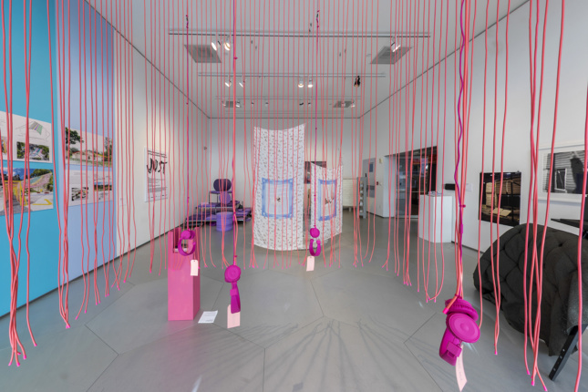 Interior of an exhibition with pink string suspended from the ceiling