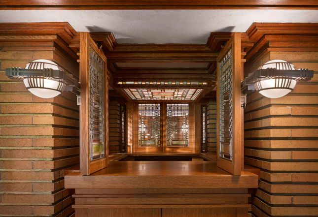Intricate glasswork in a doorframe flanked by two lights at the Martin House