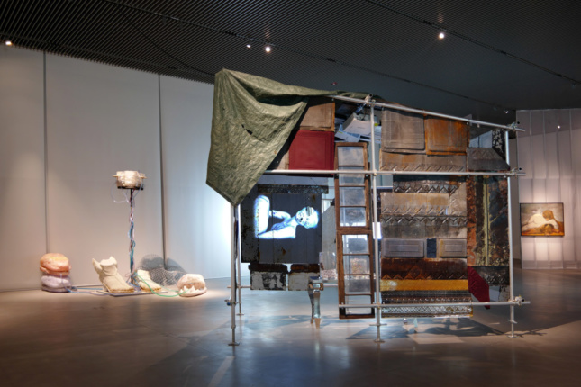 An installation view of different materials draped over scaffolding
